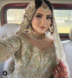 a woman wearing a bridal outfit in the back of a car with her hand on her hip