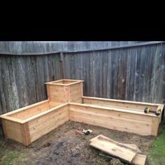 a wooden garden bench sitting in the middle of a yard next to a wood fence