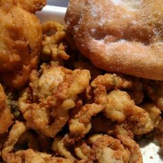 fried food is in a white container with sugar on the top, and two donuts are next to it