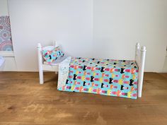 a small child's bed in the corner of a room with a wooden floor