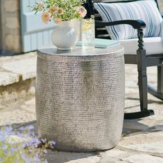 a vase with flowers sitting on top of a table next to a chair and flower pot