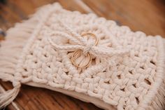 two wedding rings are tied to a white crochet bag on a wooden surface