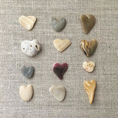 several different types of heart shaped rocks on a tablecloth with white and grey background