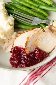 a plate with turkey, mashed potatoes, cranberry sauce and green beans