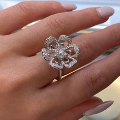 a woman's hand with a ring on it and a diamond flower in the middle