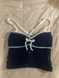 a blue and white crocheted purse with a bow on the front, sitting on a bed