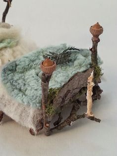 a miniature doll house made out of felt and wood, with trees on the ground