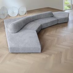 a curved couch sitting on top of a hard wood floor next to a wall with mirrors