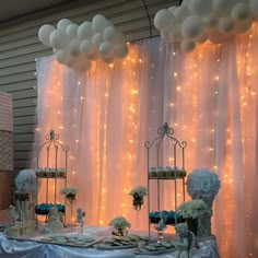 a table topped with lots of cake and desserts covered in white frosted balloons