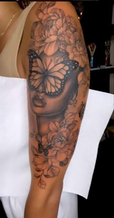 a woman's arm with a butterfly and flower tattoo on her left arm, which is covered in black and white flowers