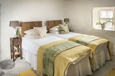 two beds in a room with white walls and yellow blankets on top of each bed