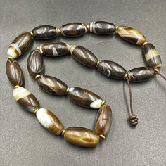 A gorgeous strand of vintage banded agate beads ,each bead has been cherry picked for its distinct high quality all of the long banded agate beads were collected in India in the 1970 Beads will display natural crystalline banding and rang in color from light browns to mostly black ,the large focal is particular beautiful Vintage Agate Beaded Necklace With Oval Beads, Vintage Agate Oval Beads, Brown Large Oval Beads, Gems, And Cabochons, Large Brown Agate Beads, Brown Large Agate Beads, Brown Polished Oval Beads, Brown Oval Natural Stone Beads, Hand-strung Oval Agate Beads, Hand-strung Brown Agate Beads