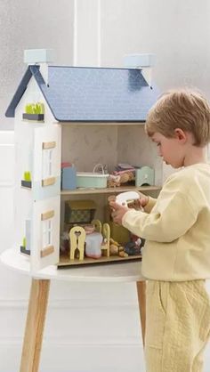 a little boy that is playing with a doll house