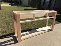 a wooden table sitting on top of a cement slab in front of a grass covered yard