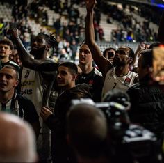 a group of men standing next to each other in front of a crowd at a basketball game