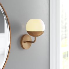 a wall mounted light next to a mirror on a gray wall in a room with white walls