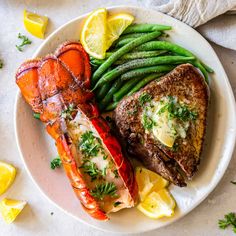 lobster, green beans and lemon wedges on a white plate with some garnish