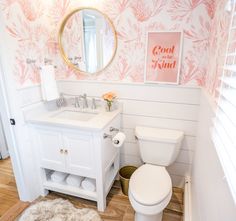 a white toilet sitting next to a sink in a bathroom under a mirror above a vanity