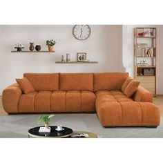 a living room with a sectional couch and coffee table in front of a clock on the wall