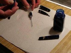 two hands are writing on a piece of paper with pens and ink bottles next to it