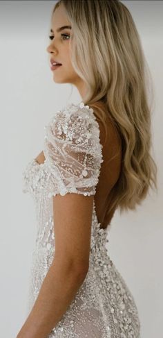 the back of a woman wearing a white dress with sequins and beads on it