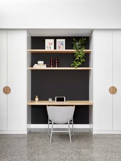 a desk and chair in a room with black walls, white cupboards and shelves