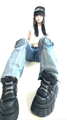 a doll sitting on top of a pair of jeans and boots with her legs crossed