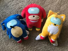 three stuffed animals laying on the floor next to each other in different colors and sizes