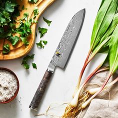 a knife sitting on top of a wooden cutting board next to some vegetables and spices