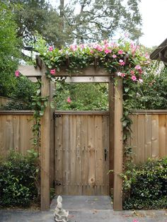 a wooden gate with pink flowers growing over it