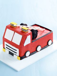 a cake shaped like a firetruck is on a white plate with blue background