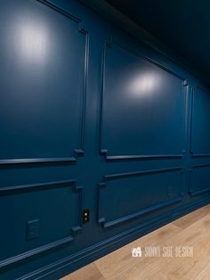 an empty room with blue walls and wooden floors