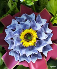 a flower made out of money sitting on top of green leaves