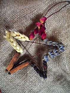 three dried flowers and two sticks on a table cloth with some brown, white, and blue stems