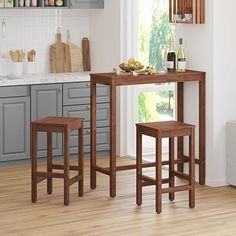 two stools and a table in a kitchen with wood flooring, gray cabinets and white walls