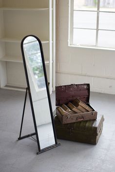 a mirror sitting on the floor next to two suitcases