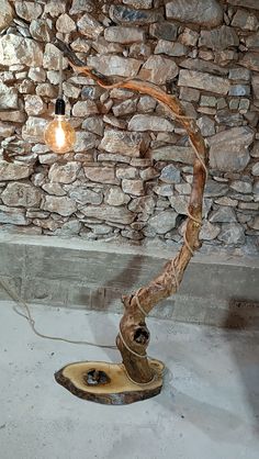 a lamp that is sitting on top of a wooden stand in front of a stone wall