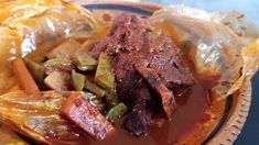 a bowl filled with meat and vegetables covered in sauce