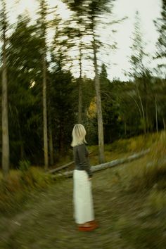 a woman walking down a dirt road in the woods