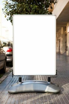 a white sign sitting on top of a sidewalk