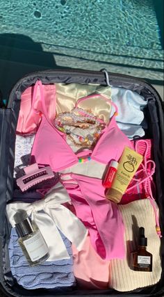 an open suitcase filled with clothing and personal care items next to a swimming pool in the background