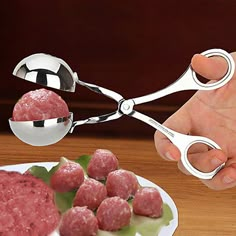 a hand holding a pair of scissor over meatballs on a plate