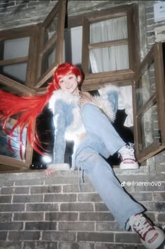 a woman with red hair sitting on top of a brick wall next to a window