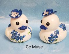 two white ducks with blue hats and flowers on them