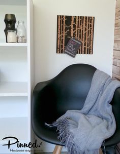 a black chair with a gray blanket on it in front of a book shelf and bookshelf