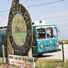 an old sign is in front of a blue bus and some telephone poles on the side of the road