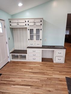 an empty room with white cabinets and wood floors