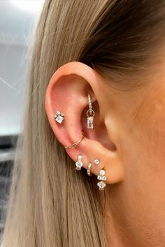 a woman with blonde hair wearing three different ear piercings on her left side and one behind the ear