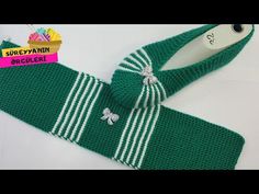 a green knitted tie with white stripes and a clover on the side, next to a price tag