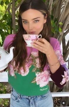 a woman is drinking out of a tea cup